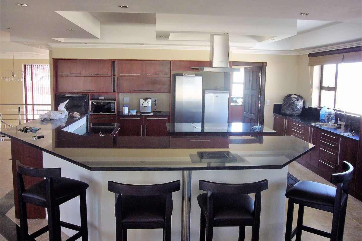 Spacious kitchen featuring dark wood cabinetry, granite countertops, a large breakfast bar, and stainless steel extractor fan.