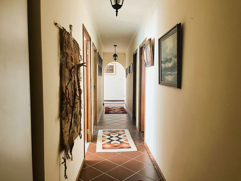 A long, well-lit hallway featuring terracotta-style floor tiles, an arched transition, and multiple doorways leading to other areas of the home.