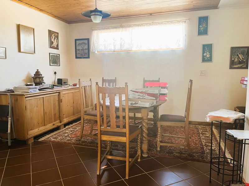 A dining room featuring a timber-clad ceiling, tiled flooring, and a horizontal window, providing a functional space for family meals.