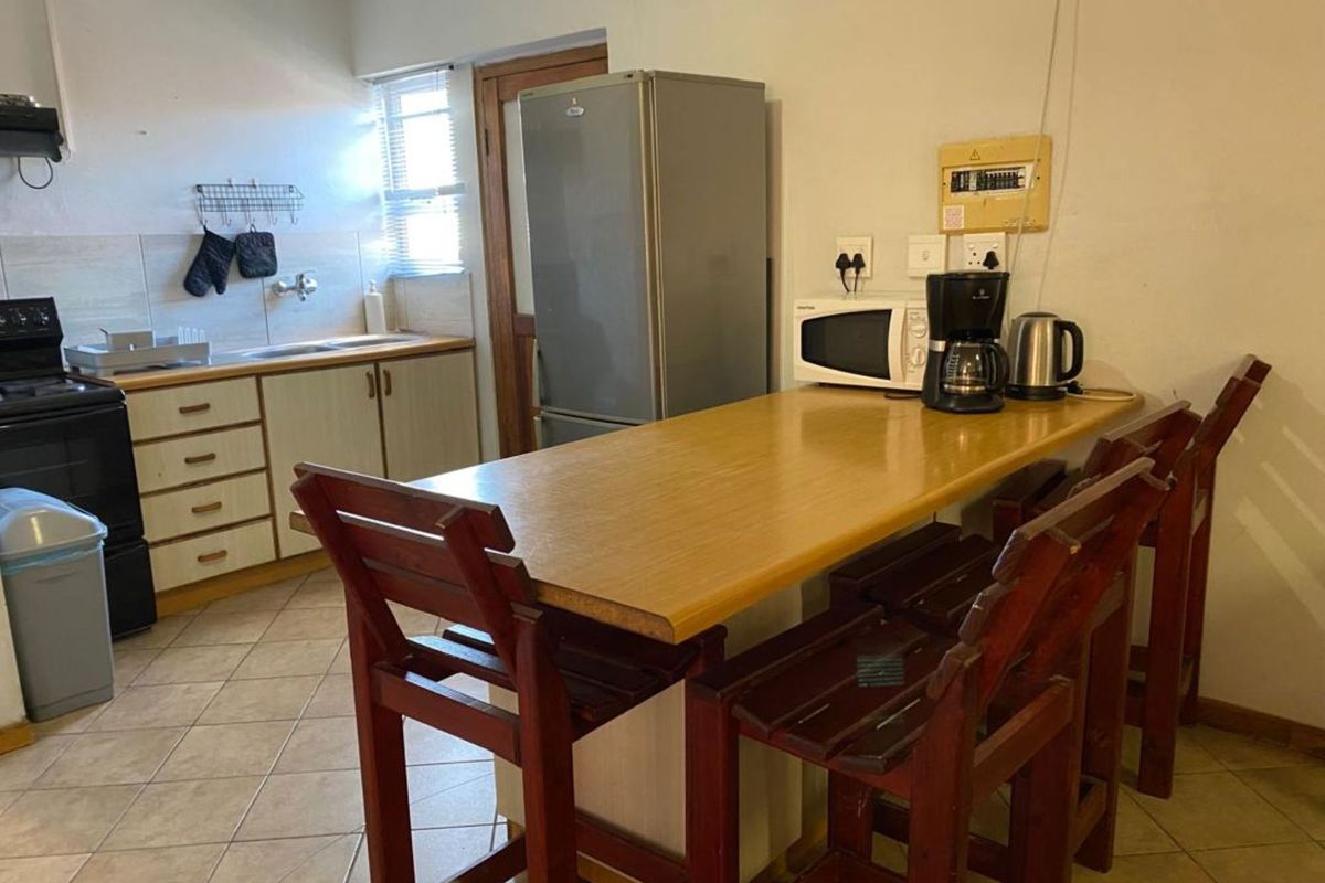 A functional kitchen area featuring tiled flooring, built-in cabinetry, a sink, and a breakfast bar counter.