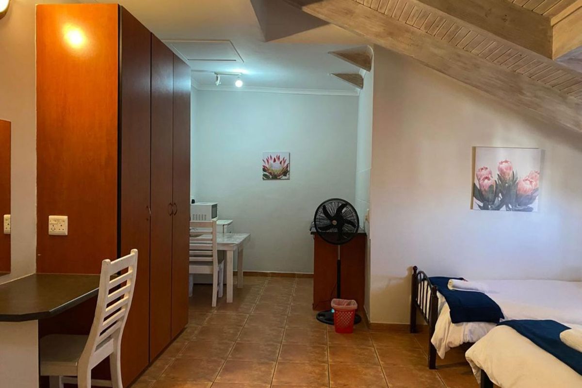 A bedroom featuring a pitched timber ceiling, tiled flooring, and built-in wooden cabinetry, offering a functional and cozy living space.