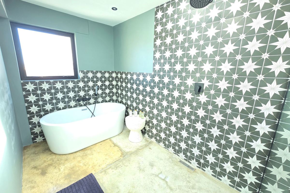 Modern bathroom featuring a freestanding bathtub, a walk-in shower with patterned wall tiles, and polished concrete flooring.