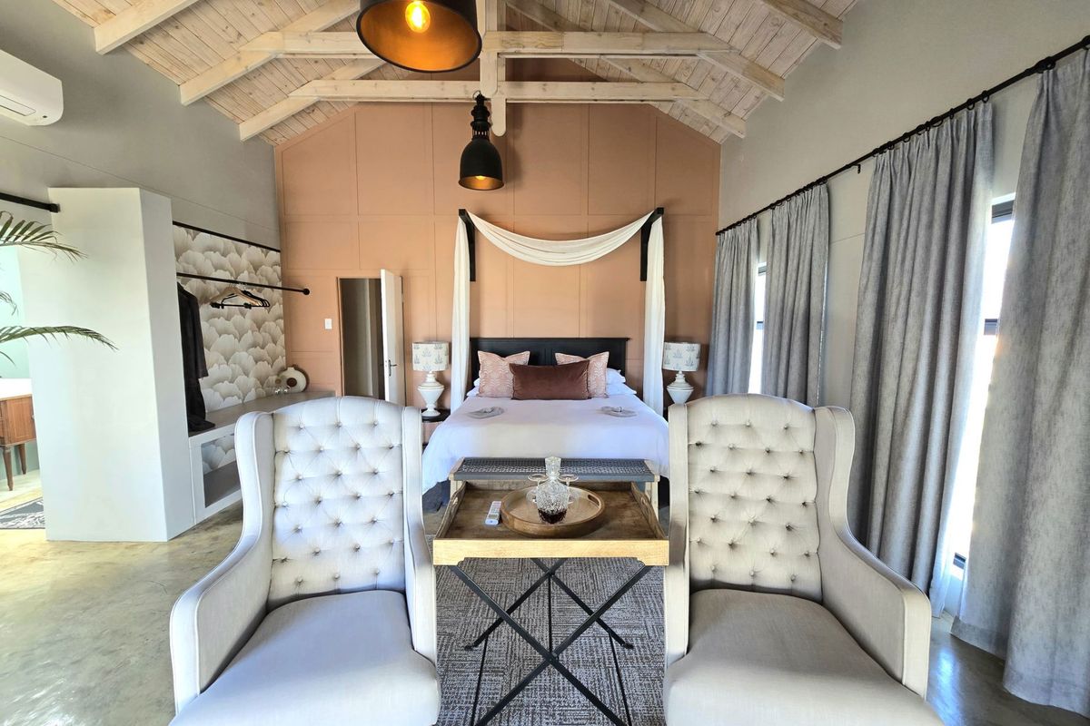 Spacious bedroom featuring exposed timber ceiling beams, elegant wall paneling, and a built-in wardrobe, creating a warm and inviting atmosphere.