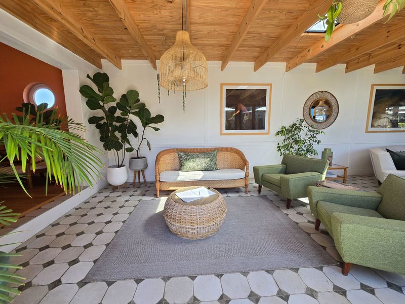 A bright living area featuring an exposed timber beam ceiling, unique patterned floor tiles, and a skylight, creating a warm and inviting atmosphere.