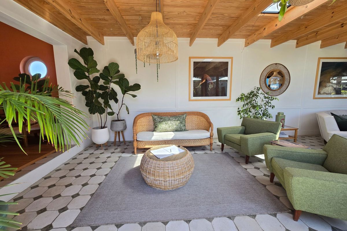 A bright living area featuring an exposed timber beam ceiling, unique patterned floor tiles, and a skylight, creating a warm and inviting atmosphere.