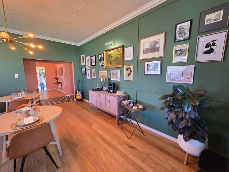 A well-maintained dining area featuring hardwood flooring, decorative wainscoting, and crown molding, with an open transition to an adjacent room.