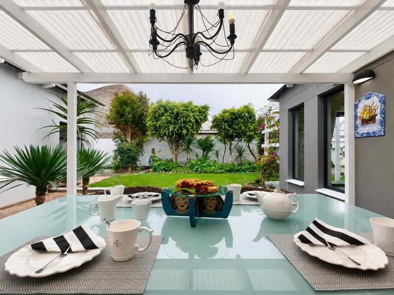 A covered outdoor patio area featuring a timber pergola with a translucent roof, overlooking a well-maintained garden.