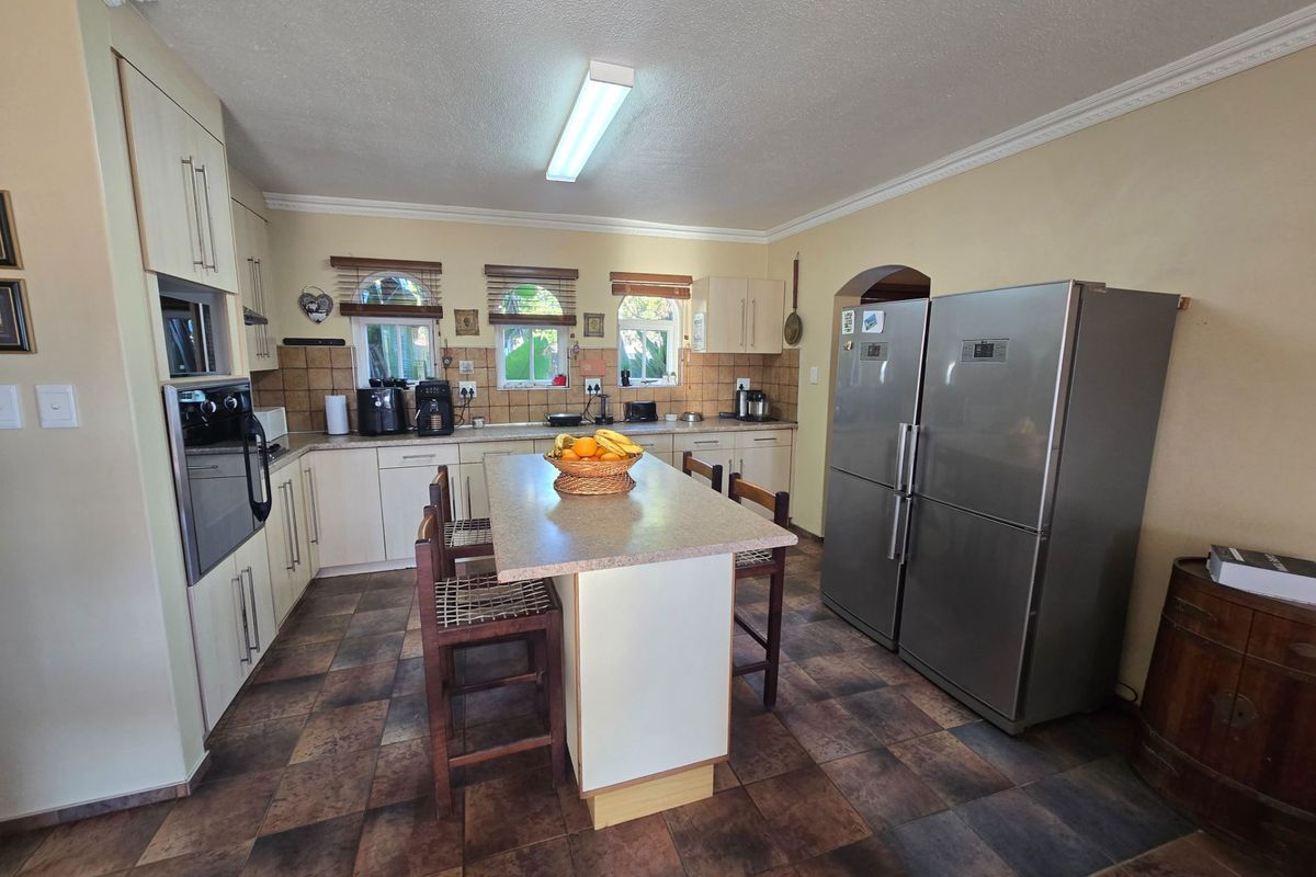 A functional kitchen featuring built-in cabinetry, a central island with seating, tiled flooring, and integrated appliances, offering a practical layout for daily use.