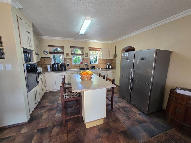 A functional kitchen featuring built-in cabinetry, a central island with seating, tiled flooring, and integrated appliances, offering a practical layout for daily use.