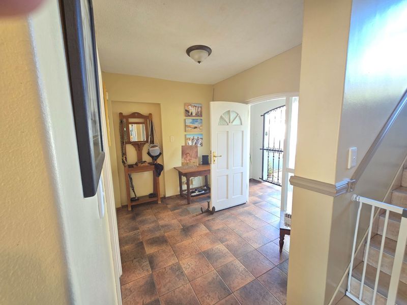 Welcoming entrance foyer featuring tiled flooring, a staircase, and direct access to the exterior through a security gate.