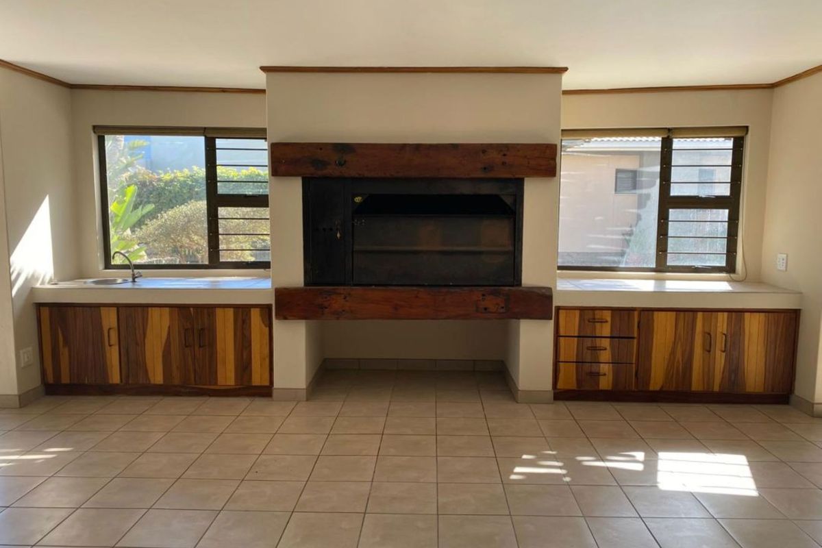 Spacious living area featuring a prominent built-in fireplace with timber mantel, integrated cabinetry, and tiled flooring, offering a functional and versatile space.