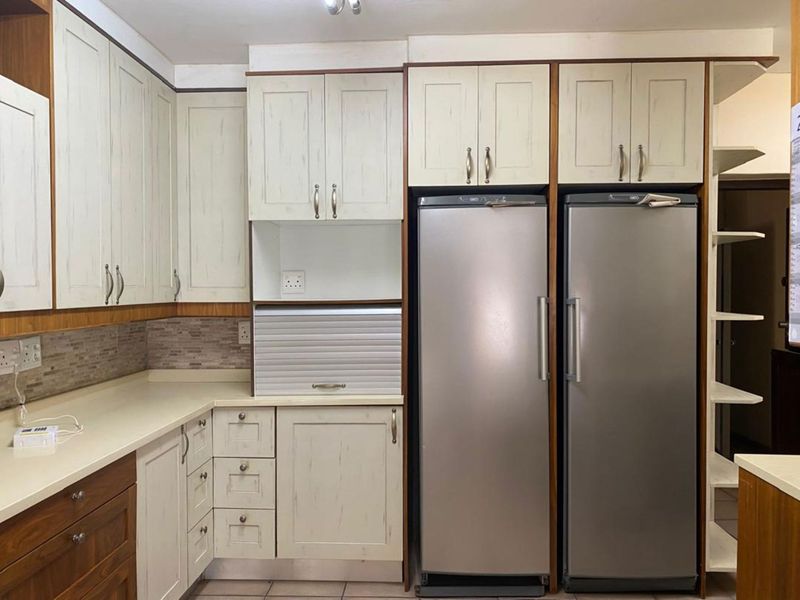 A well-maintained kitchen featuring custom cabinetry, integrated appliance storage, tiled backsplash, and dedicated space for side-by-side refrigeration units.