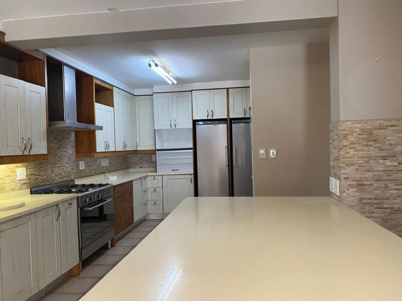 A well-appointed kitchen featuring stone countertops, built-in cabinetry, a gas stove with extractor fan, and a functional kitchen island.