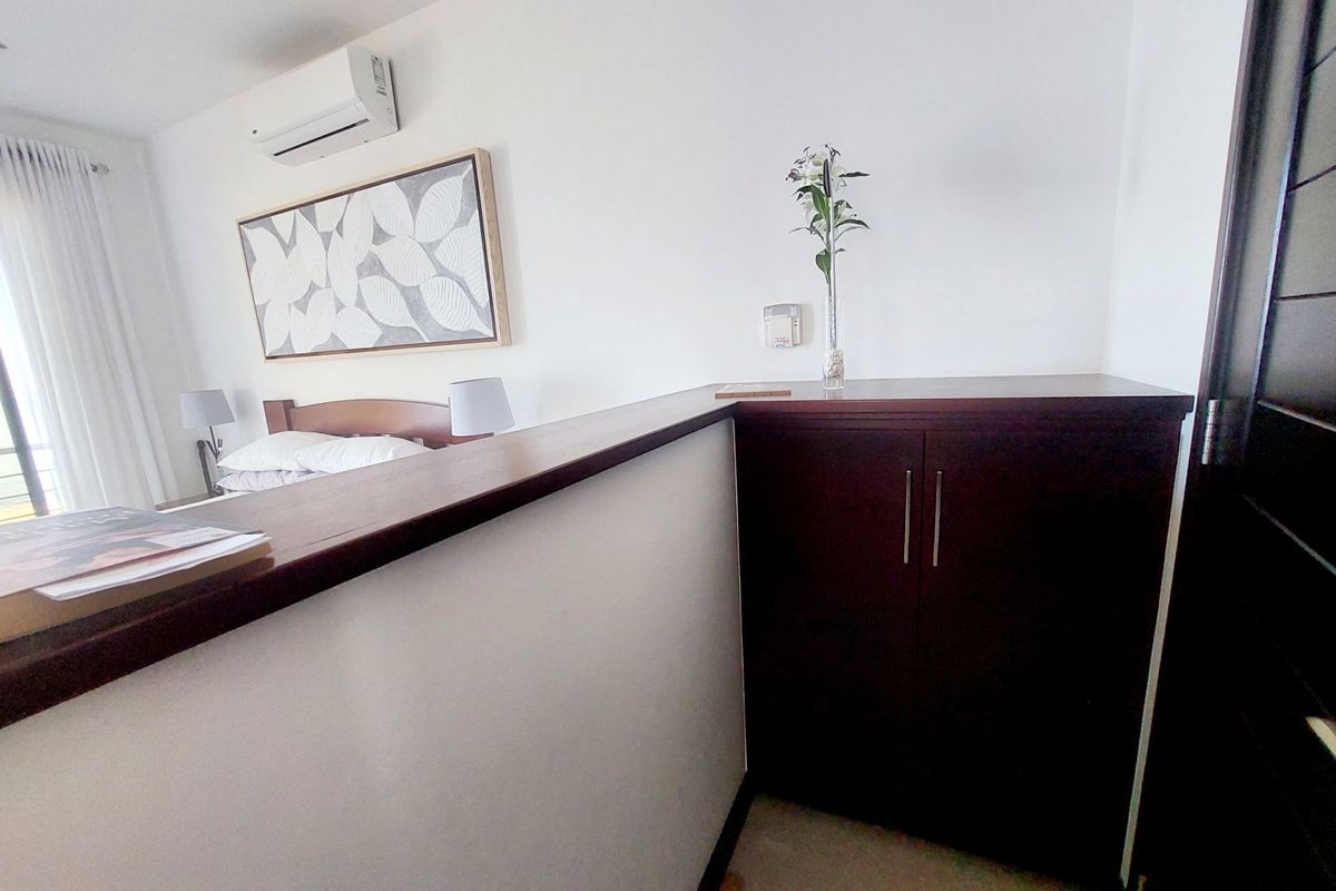 A bedroom featuring a timber partition shelf, built-in cabinetry, and a wall-mounted split-system air conditioner.