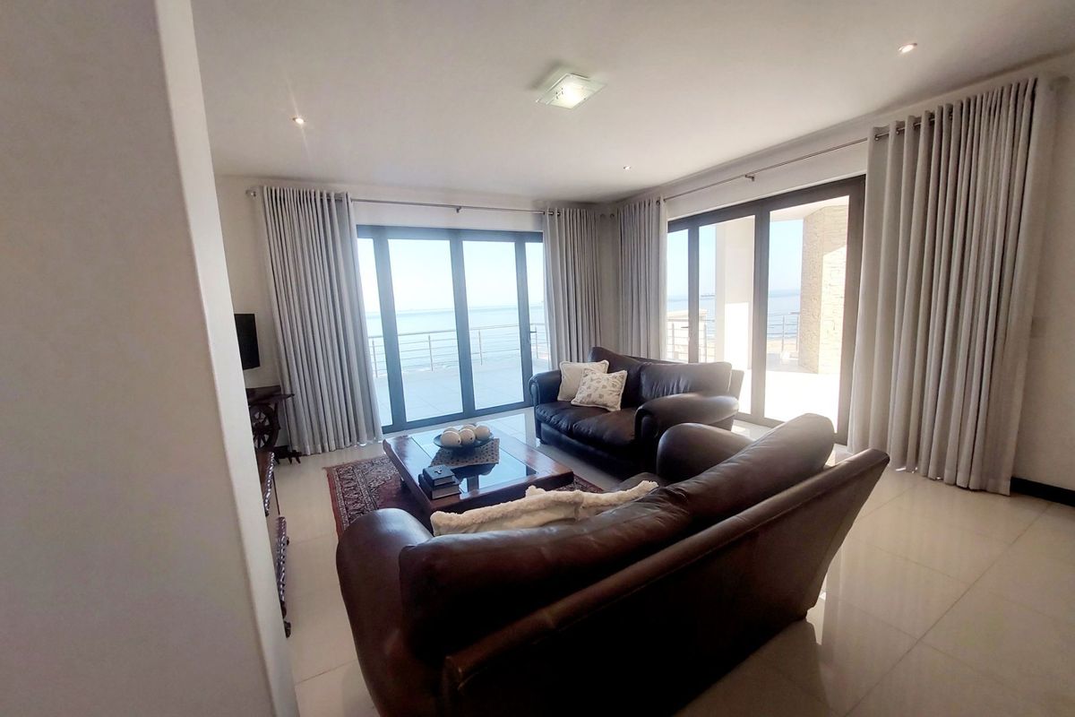 Spacious living room featuring large sliding glass doors that provide ample natural light and direct access to an outdoor area with ocean views.