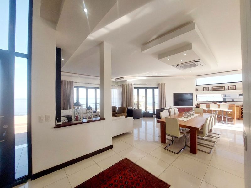 Spacious open-plan living and dining area featuring high ceilings, recessed lighting, tiled floors, and large sliding doors leading to an outdoor space.