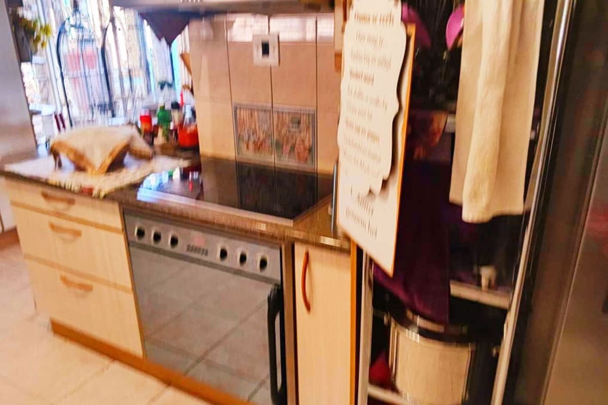 A functional kitchen area featuring built-in cabinetry, a stone countertop, an electric hob, and an integrated oven with an overhead extractor fan.