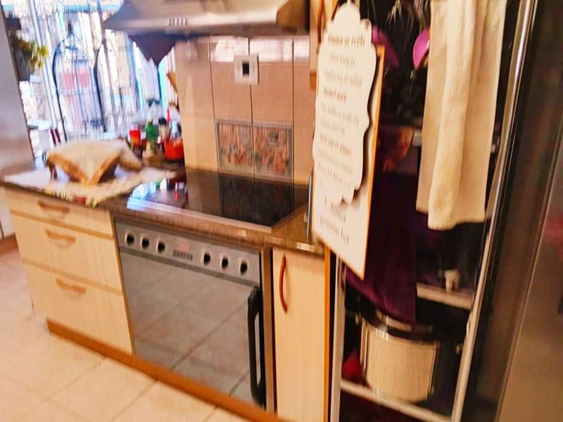 A functional kitchen area featuring built-in cabinetry, a stone countertop, an electric hob, and an integrated oven with an overhead extractor fan.