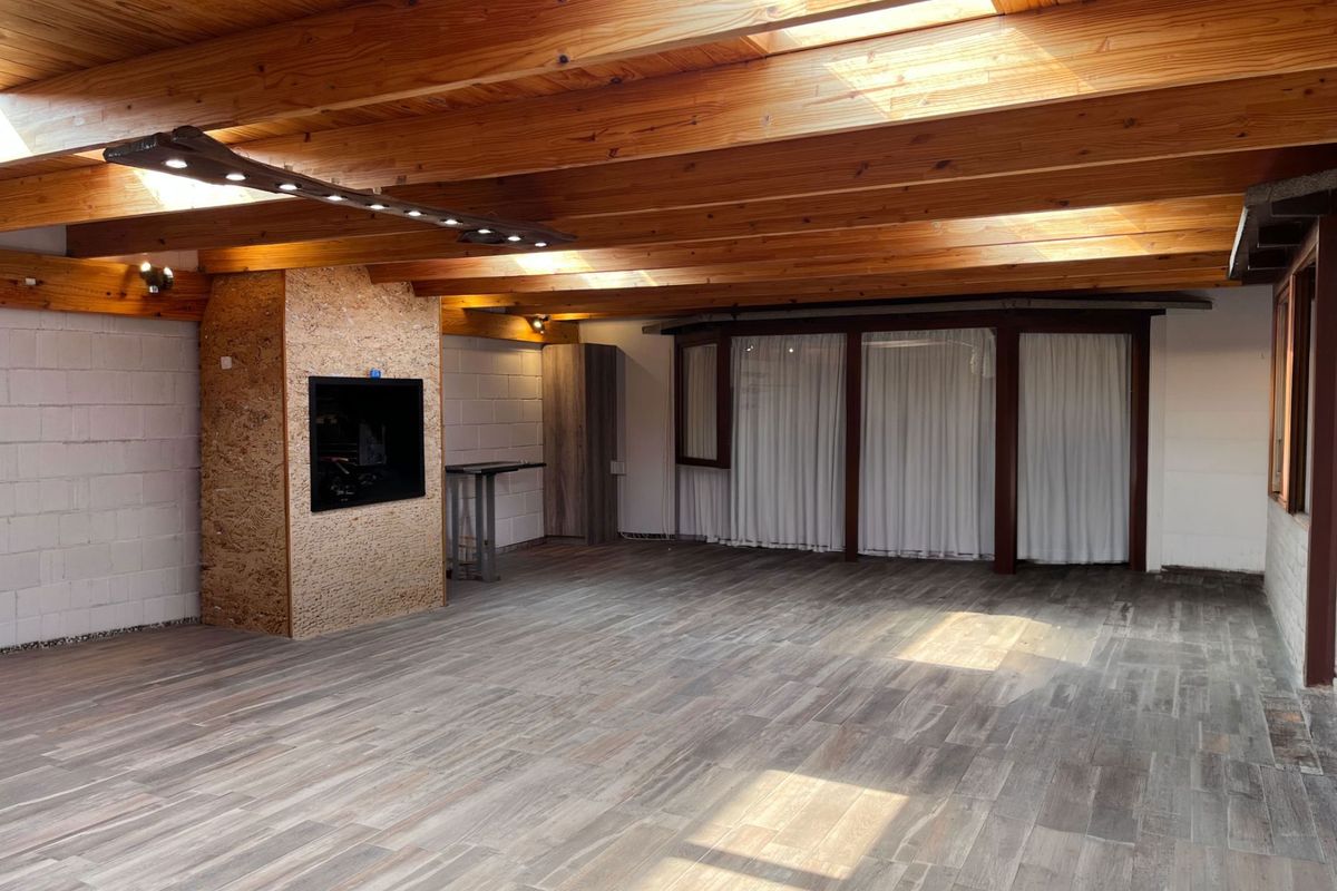 Spacious living area featuring exposed timber beam ceilings with integrated skylights, tiled flooring, and a central built-in fireplace.