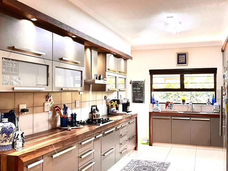 Modern kitchen featuring sleek cabinetry, warm wooden countertops, a gas hob with extractor fan, and a functional sink area with natural light.