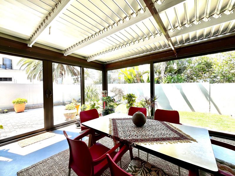 A covered patio area featuring a corrugated metal roof and large sliding glass doors that provide seamless access to the garden.