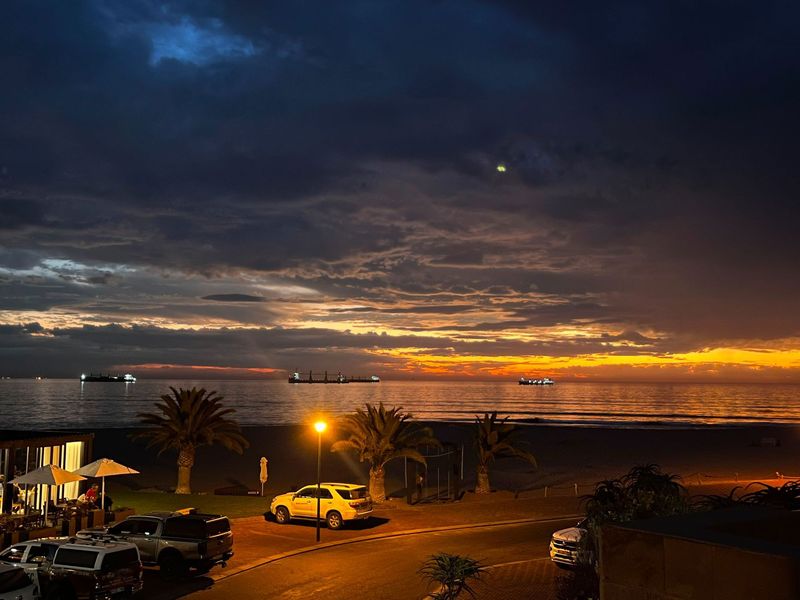 A stunning evening view overlooking the coastline, featuring a dramatic sunset over the ocean and beach area.