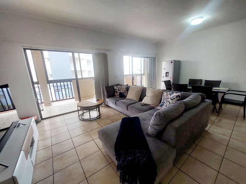 Open-plan living area featuring tiled flooring and large sliding glass doors providing access to a private balcony.