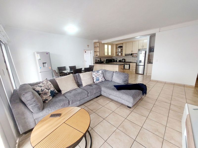 Open-plan living area featuring tiled floors and a functional kitchen with built-in cabinetry, oven, and hob, creating a spacious and connected layout.