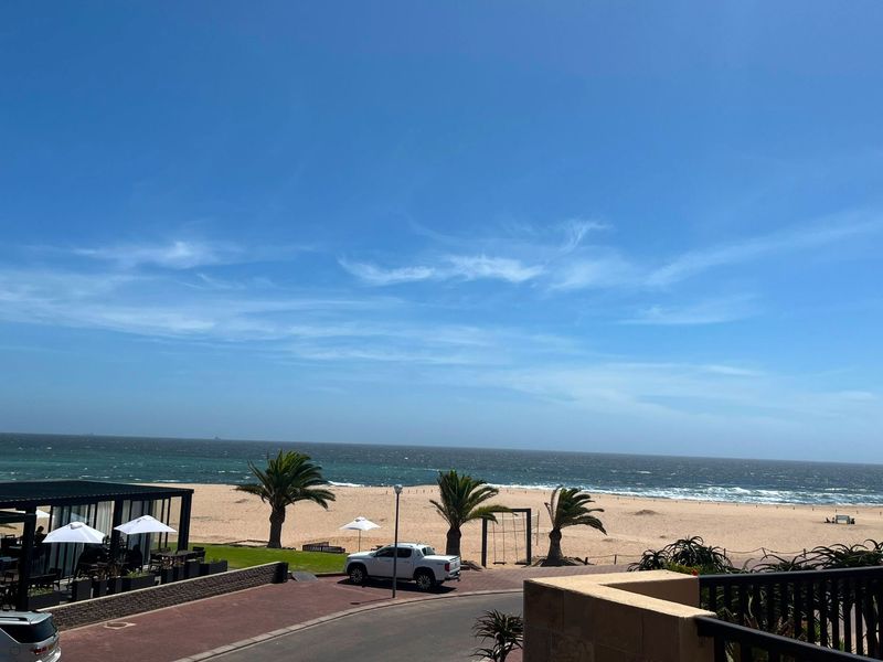 A scenic elevated view overlooking the beach, coastline, and ocean, captured from a balcony.