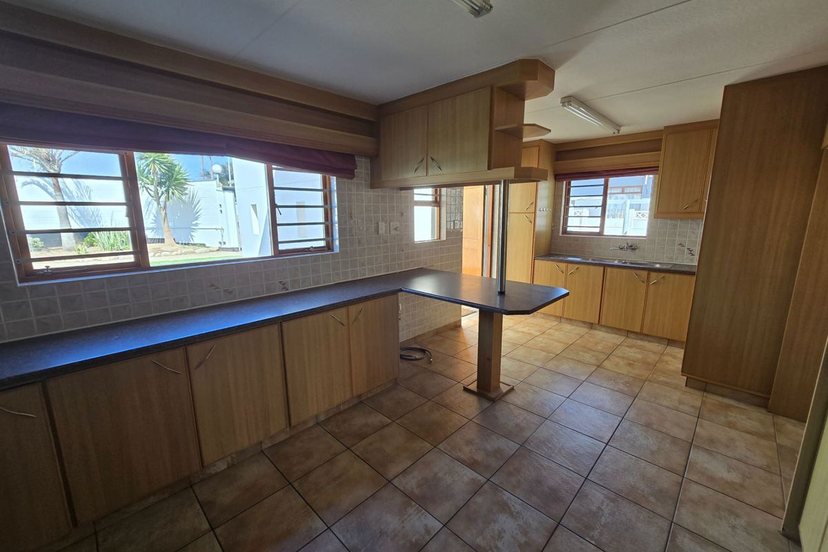 Spacious kitchen featuring extensive laminate cabinetry, a breakfast bar, tiled backsplash, and ceramic flooring, offering a functional layout ready for modern updates.
