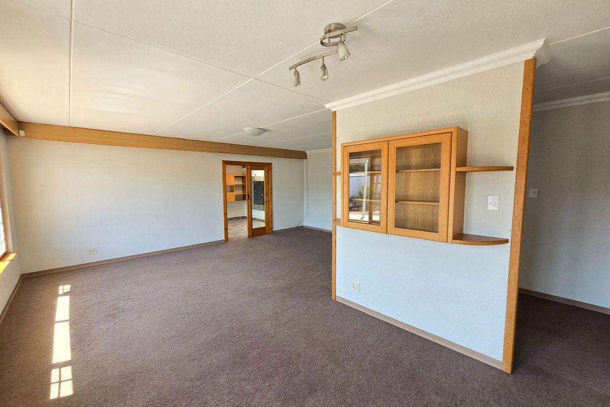 Spacious living area featuring neutral walls, carpeted flooring, and built-in wooden cabinetry, offering a versatile layout for comfortable family living.
