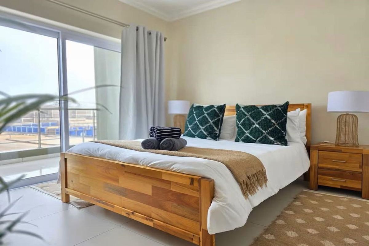 A well-maintained bedroom featuring tiled flooring and a large sliding glass door providing direct access to a private balcony.