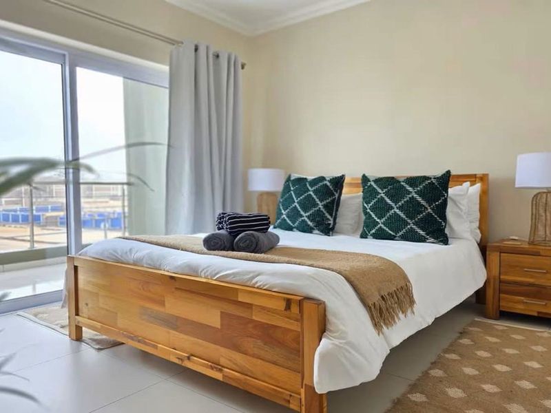 A well-maintained bedroom featuring tiled flooring and a large sliding glass door providing direct access to a private balcony.