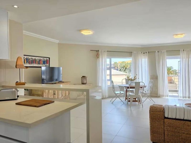 Bright open-plan living area featuring a modern kitchen island, tiled flooring, and large sliding glass doors leading to an outdoor space.