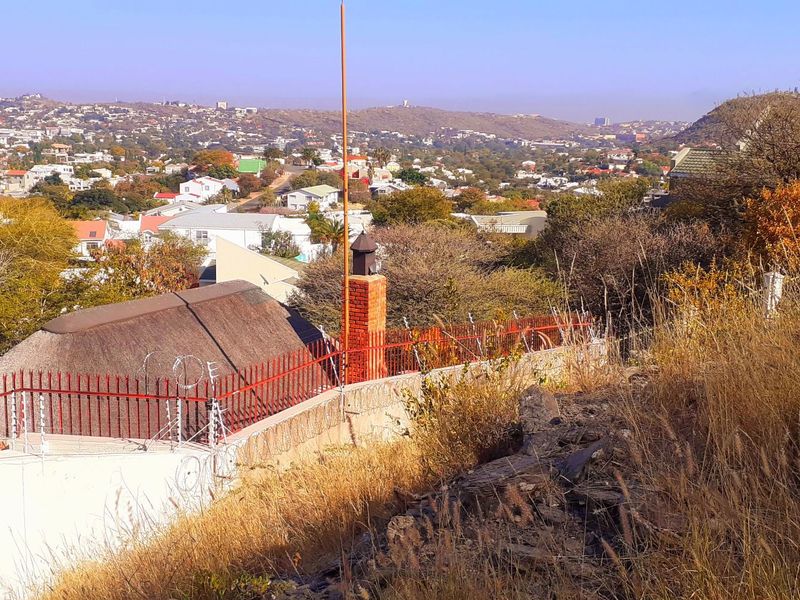 Elevated view overlooking the surrounding residential neighborhood and landscape, featuring a brick chimney and perimeter security fencing.