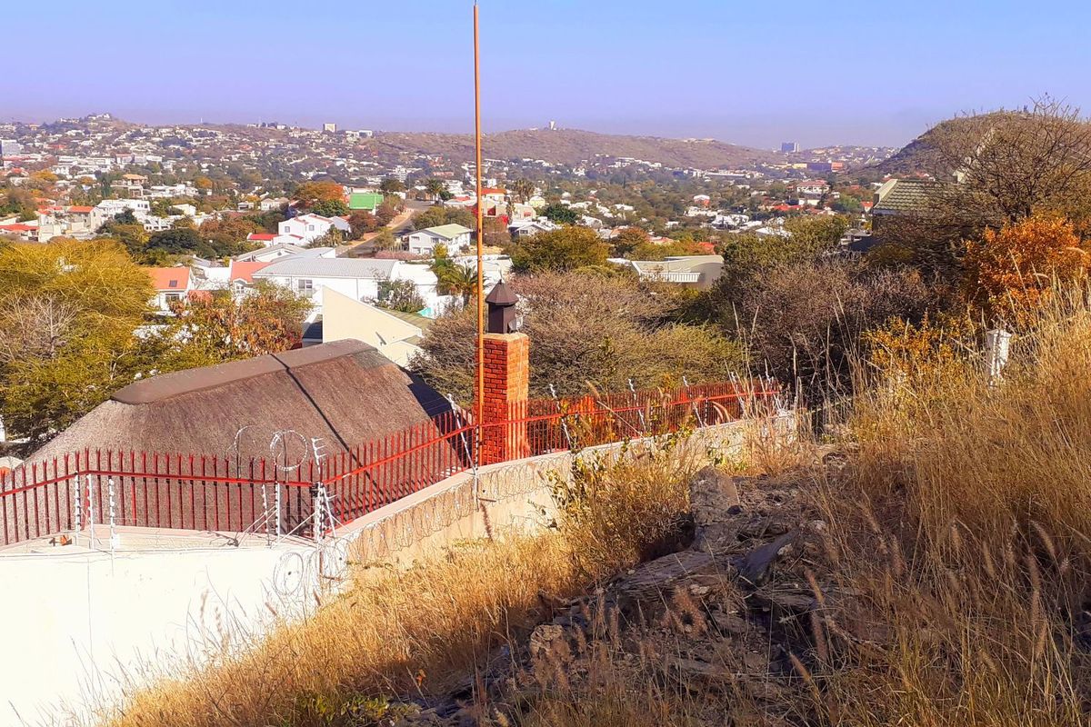 Elevated view overlooking the surrounding residential neighborhood and landscape, featuring a brick chimney and perimeter security fencing.