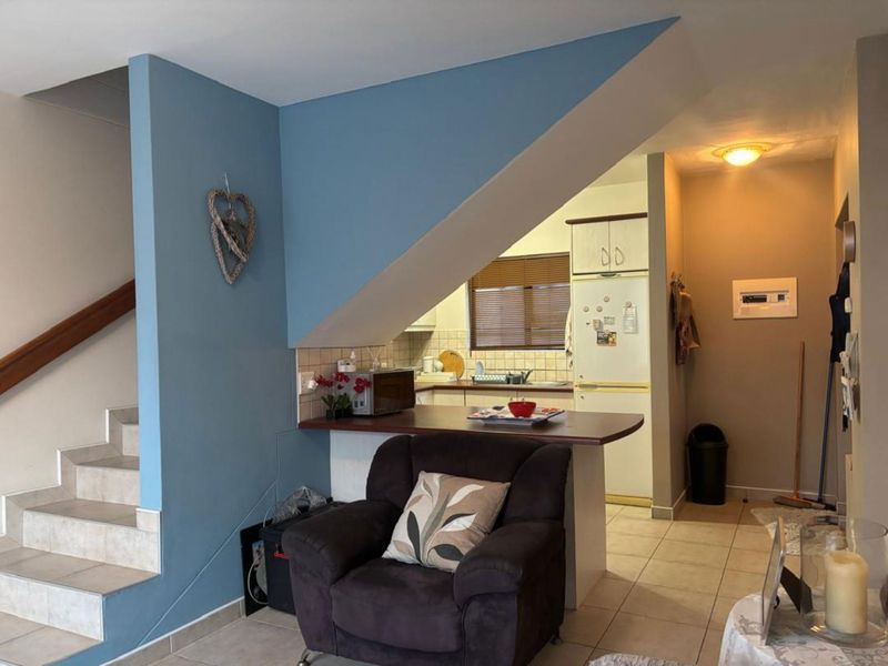 Open plan living area featuring a staircase, tiled flooring, and a functional kitchen with a breakfast bar counter.