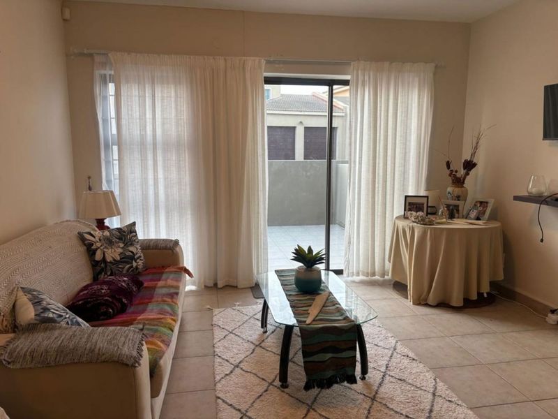 A living room featuring tiled flooring and a sliding glass door that provides access to an outdoor patio area.