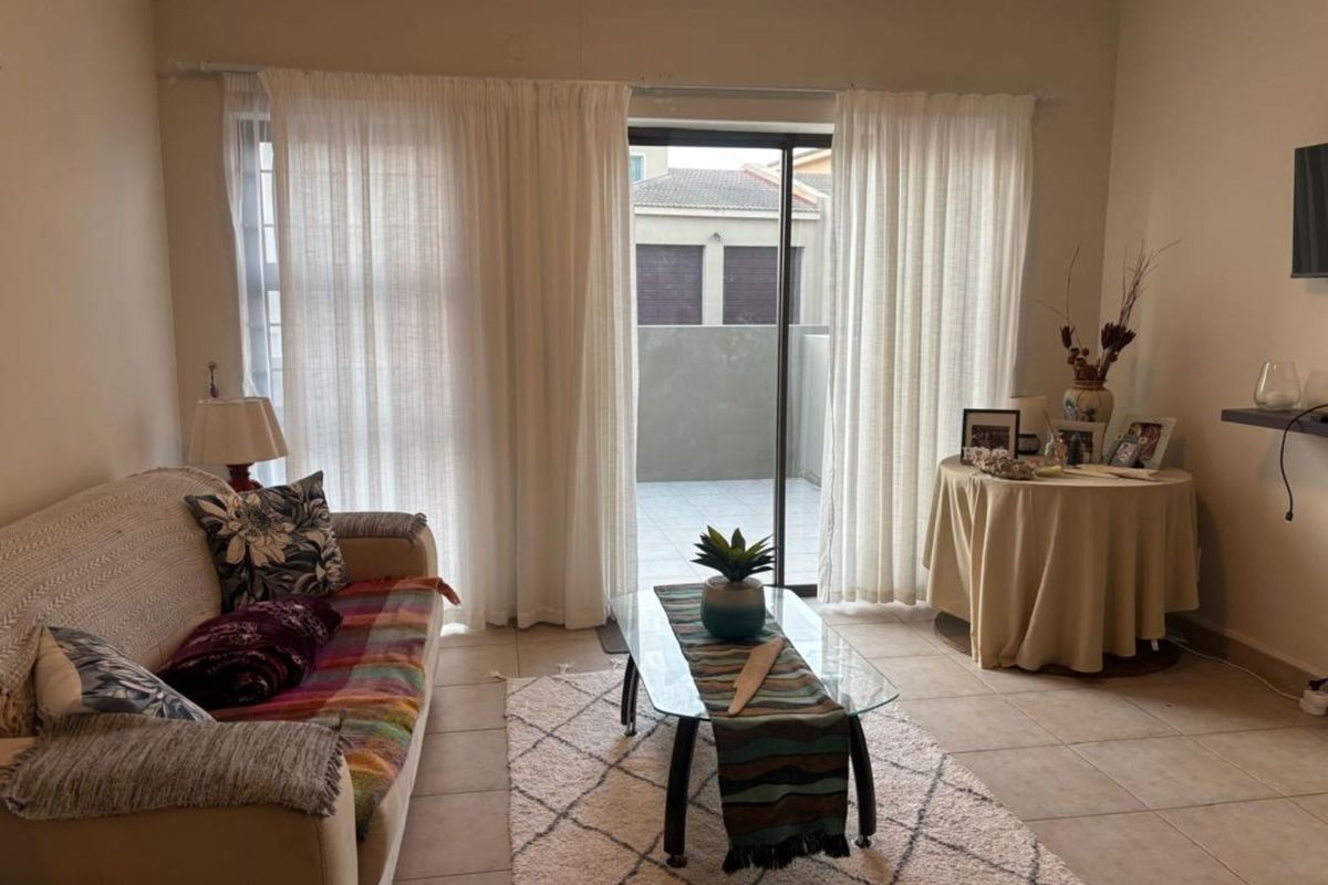 A living room featuring tiled flooring and a sliding glass door that provides access to an outdoor patio area.