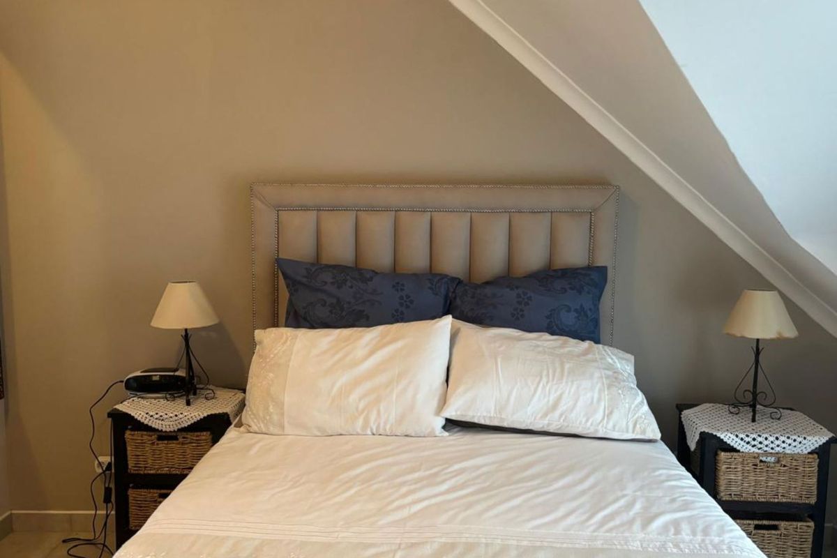 A cozy bedroom featuring a sloped ceiling and neutral wall tones, providing a comfortable and intimate sleeping space.