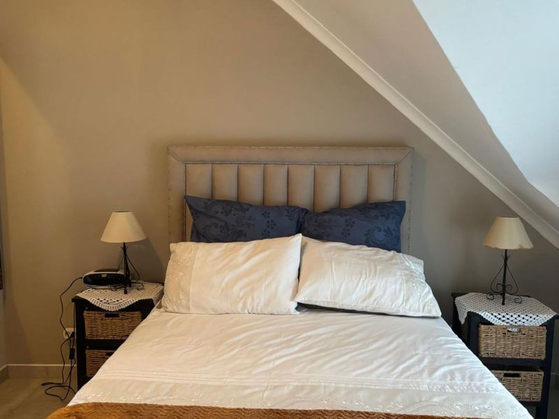A cozy bedroom featuring a sloped ceiling and neutral wall tones, providing a comfortable and intimate sleeping space.
