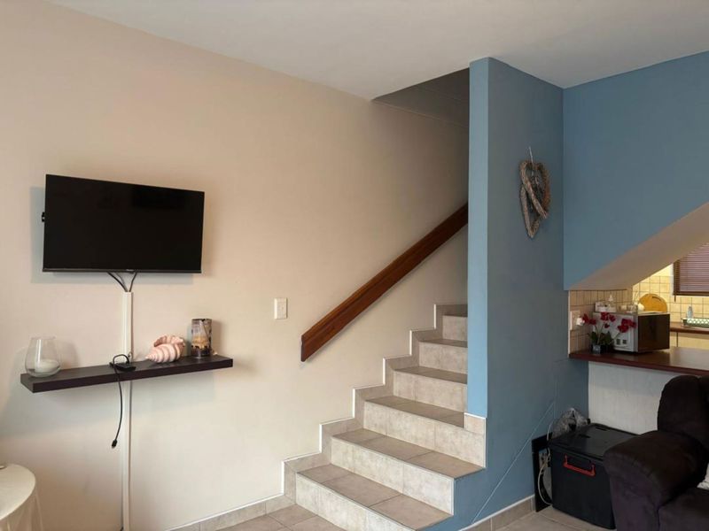 A living area featuring a tiled staircase with a wooden handrail, connecting levels within the townhouse.