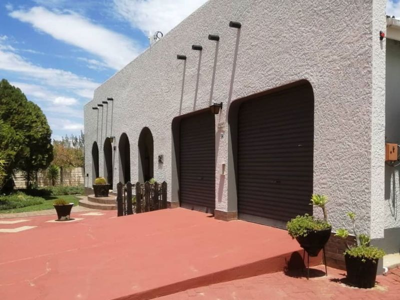 Front exterior view of the property featuring a double garage, arched architectural details, and a paved driveway area.