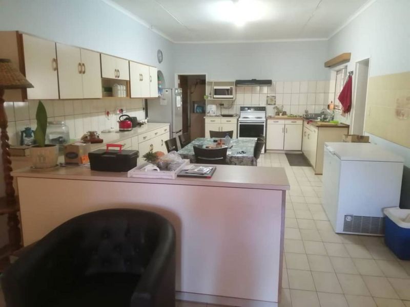 Spacious kitchen featuring ample built-in cabinetry, tiled backsplash, integrated cooking appliances, and tiled flooring, offering a functional layout for daily meal preparation.