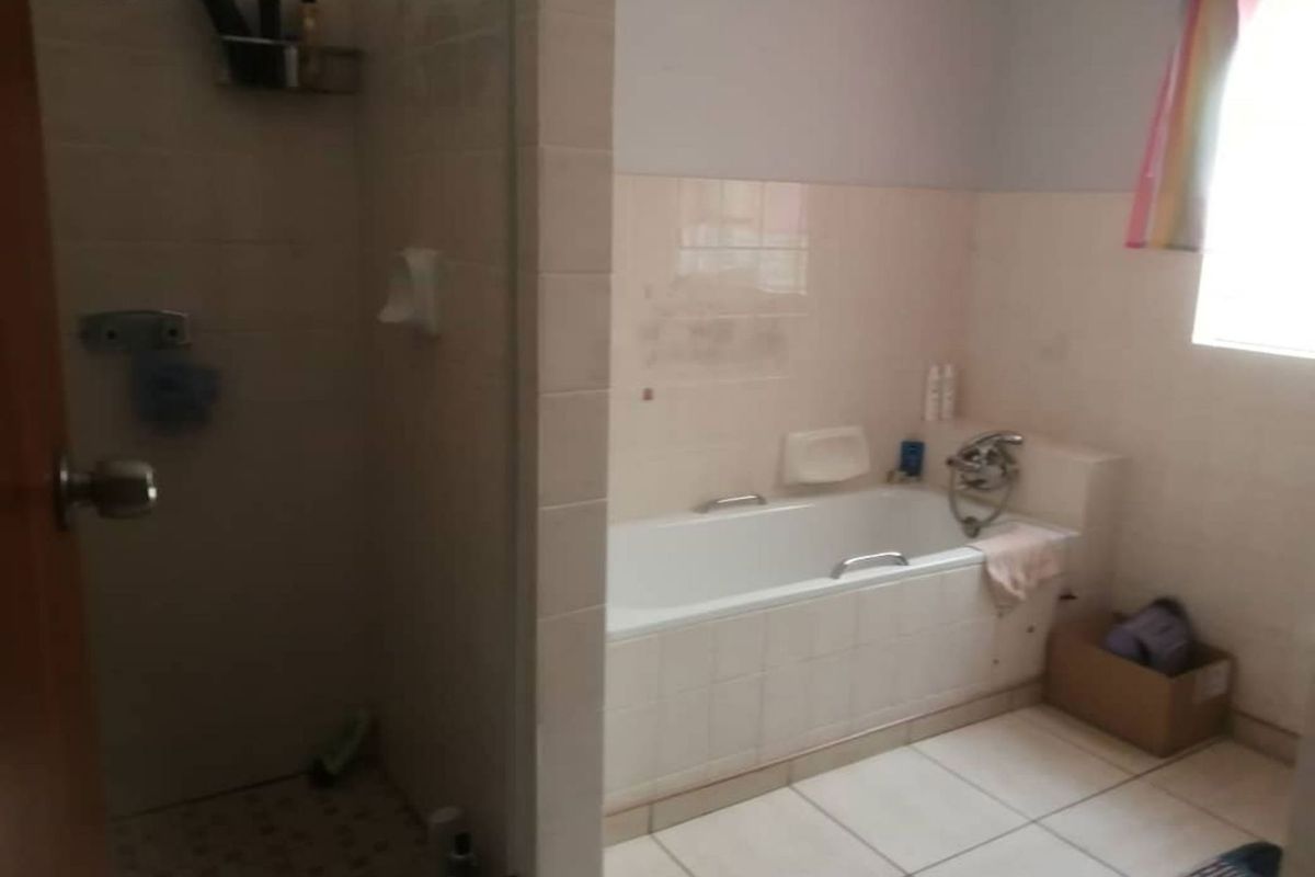 A functional bathroom featuring a built-in bathtub, a separate shower enclosure, and neutral wall and floor tiling.