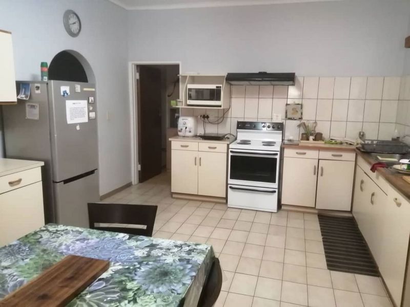 Functional kitchen featuring tiled flooring, built-in cabinetry, a tiled splashback, and a freestanding oven with an extractor fan.