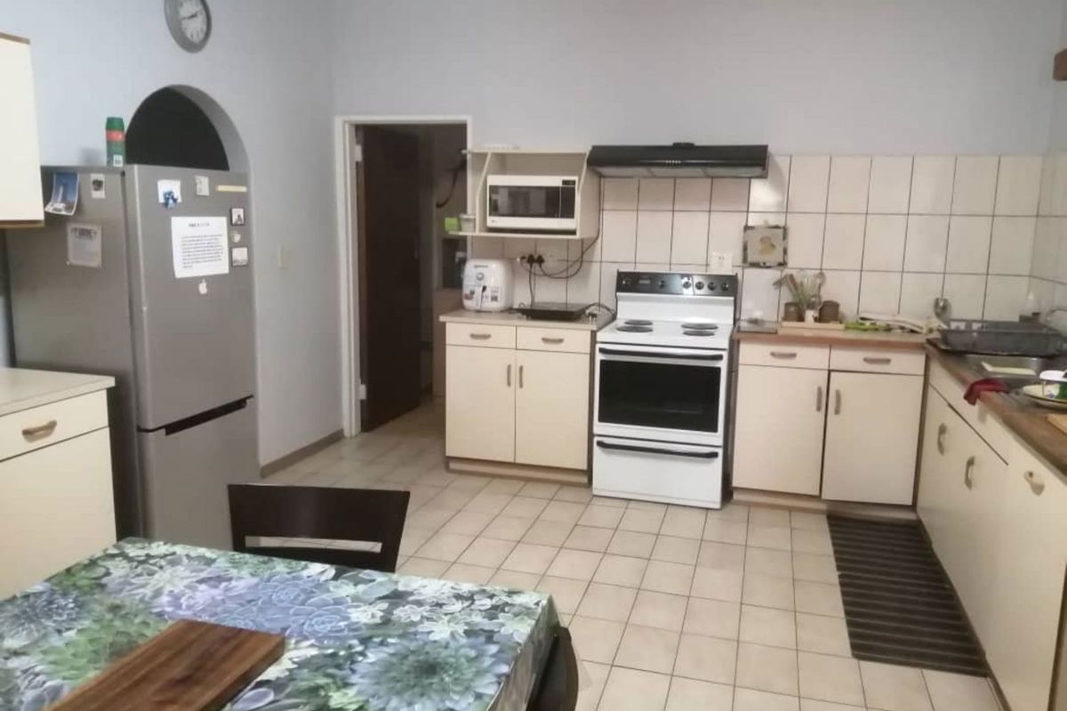 Functional kitchen featuring tiled flooring, built-in cabinetry, a tiled splashback, and a freestanding oven with an extractor fan.