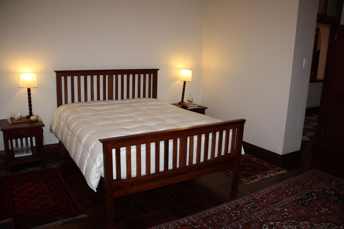 A bedroom featuring dark wood flooring and neutral walls, providing a simple and functional sleeping space.
