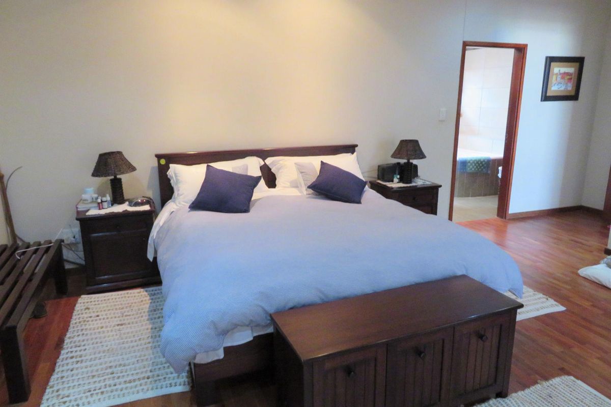 A spacious bedroom featuring warm-toned hardwood flooring and an en-suite bathroom entrance, providing a comfortable and functional living space.