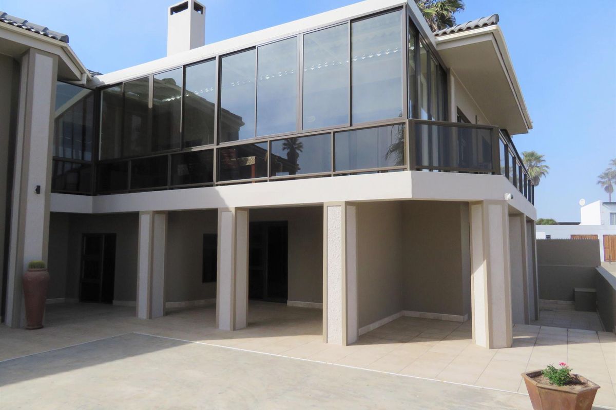A spacious rear exterior view featuring a covered patio area on the ground floor and an enclosed glass balcony on the upper level.